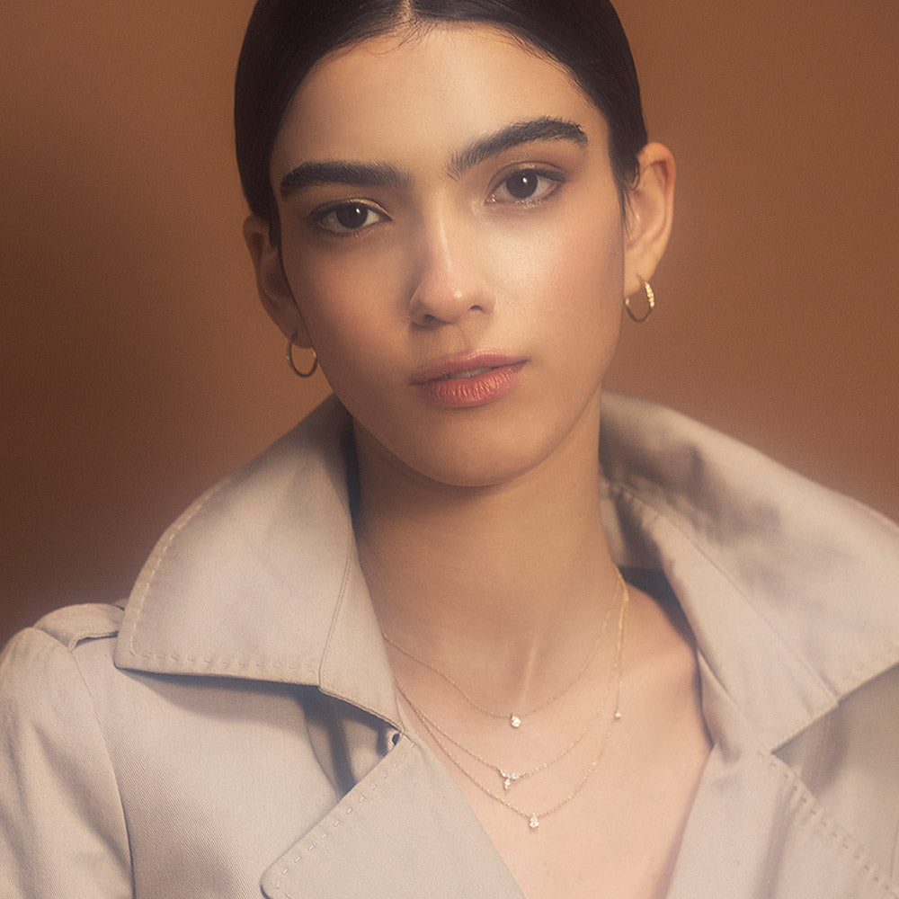 Delicate gold hoop earrings set with a row of 5 diamonds of different sizes