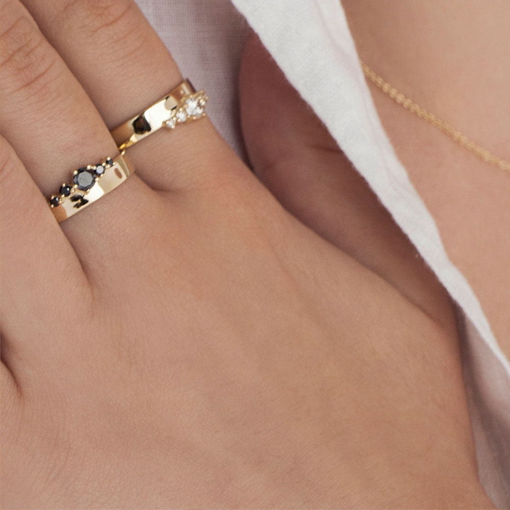 A wide gold ring with a special asymmetrical setting of black diamonds