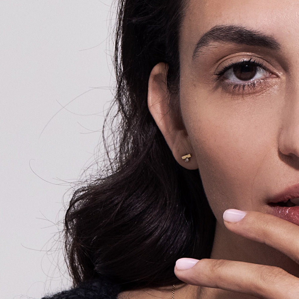 Gold earrings, tight, small, in the form of a stripe, set with a diamond