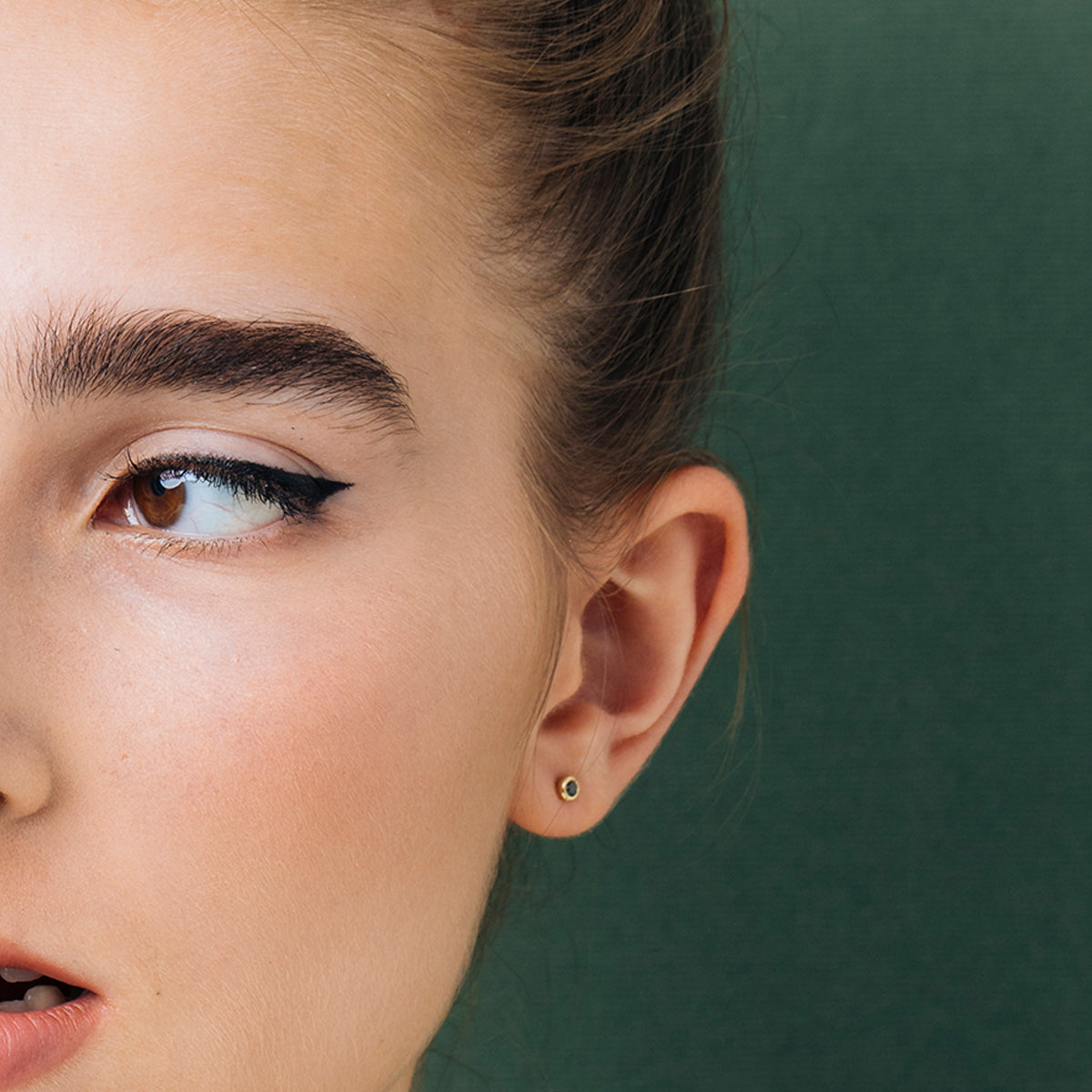 Close-fitting black diamond earrings set in a thin gold frame