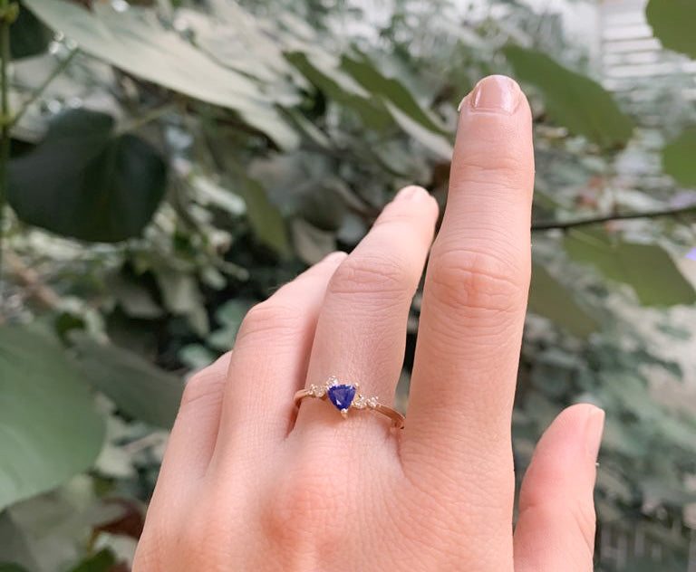 An engagement ring set with a trillion-cut sapphire and diamonds all around