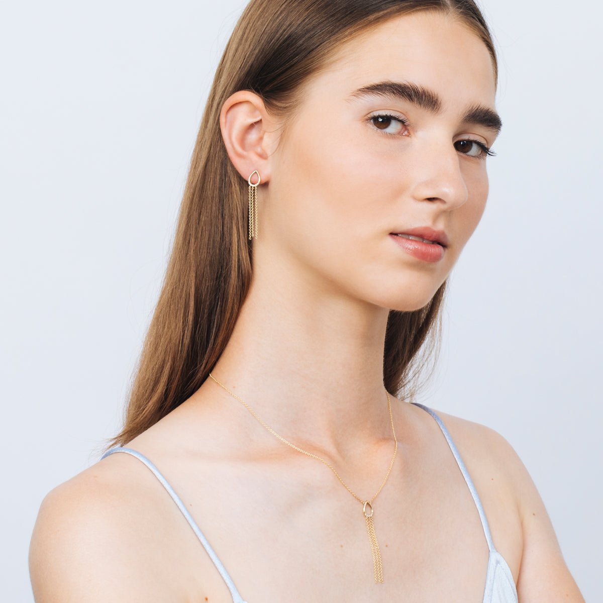 Drop-shaped gold earrings with hanging chains studded with diamonds