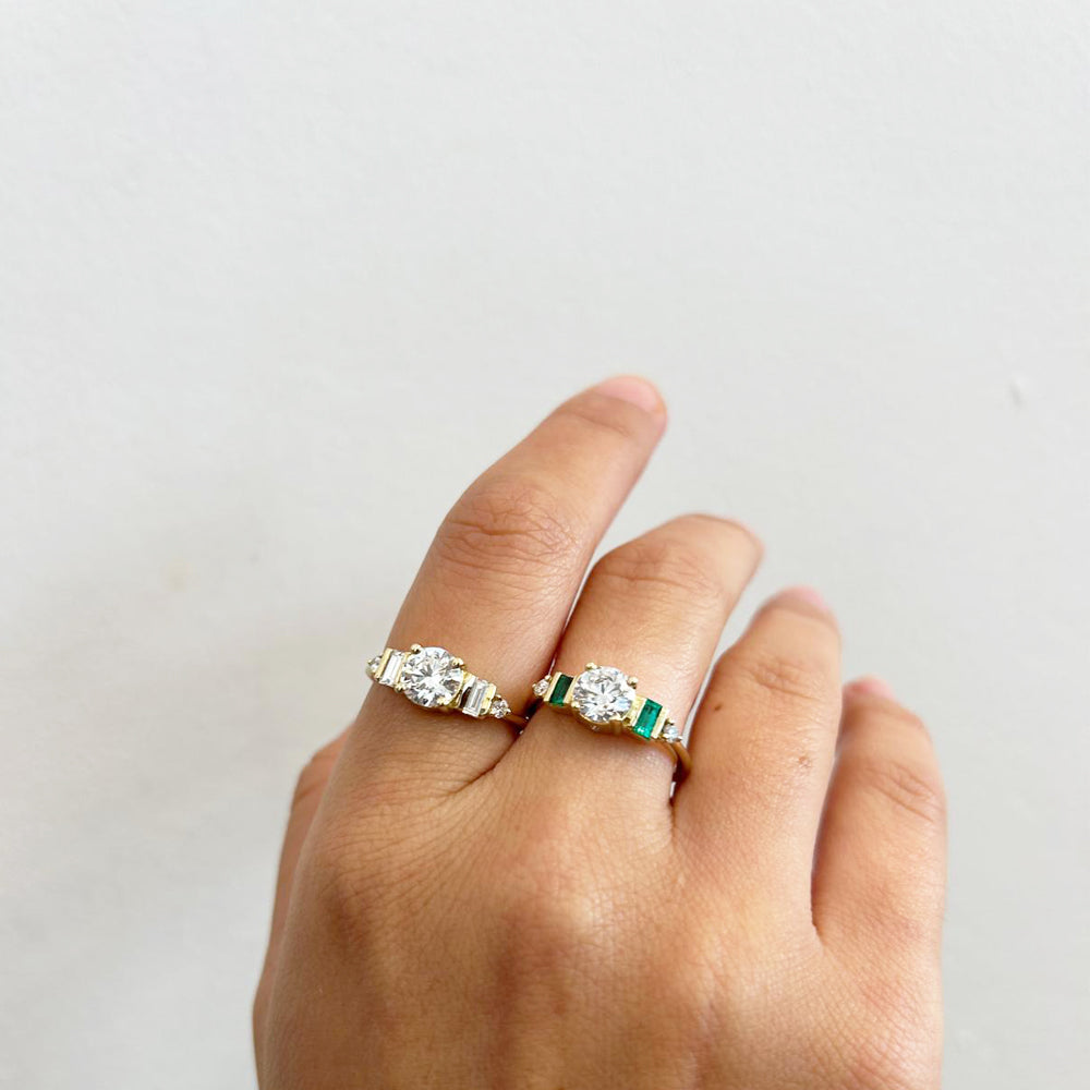 An engagement ring in gold and laboratory diamonds in a unique design of round diamonds and emeralds