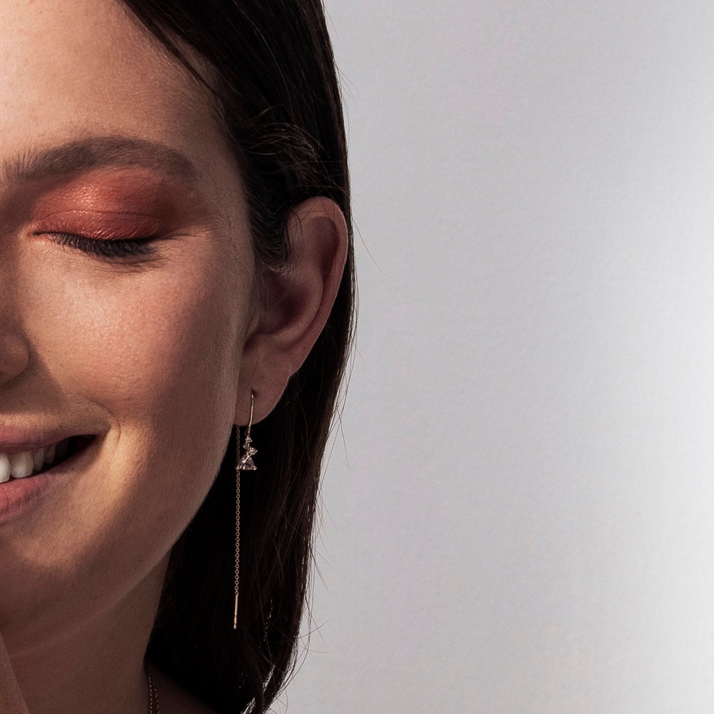 Gold earrings with a chain set with trillion-cut morganite and small diamonds of varying sizes