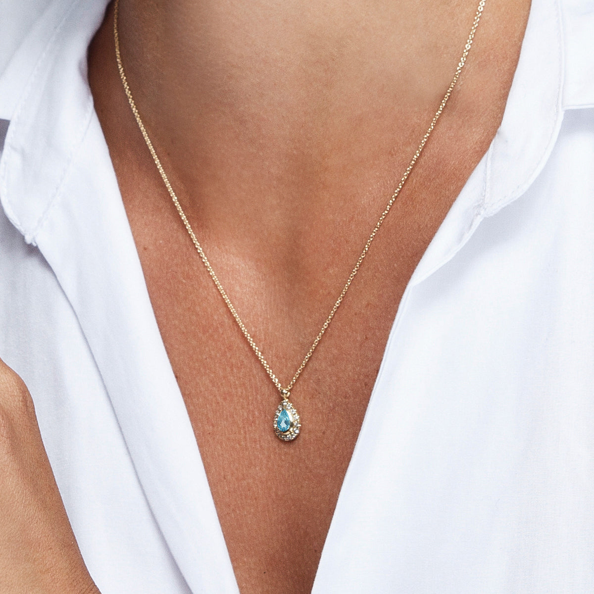 A classic gold chain, a pendant inlaid with blue topaz in the shape of a drop and diamonds all around