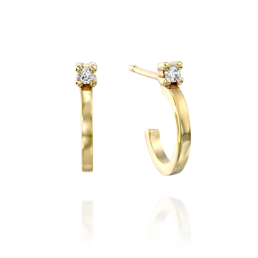 Small gold hoop earrings set with a white diamond close to the ear