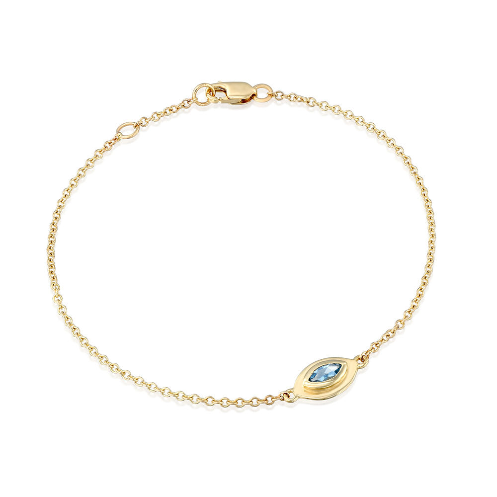 A gold bracelet in the style of the evil eye inlaid with an aquamarine stone in a marquise cut