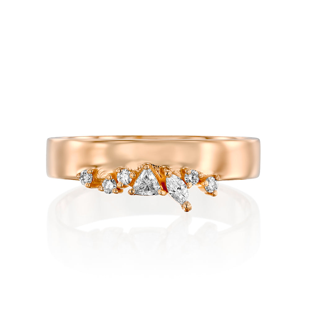 A wide gold ring with a special asymmetric setting of diamonds in a variety of cuts