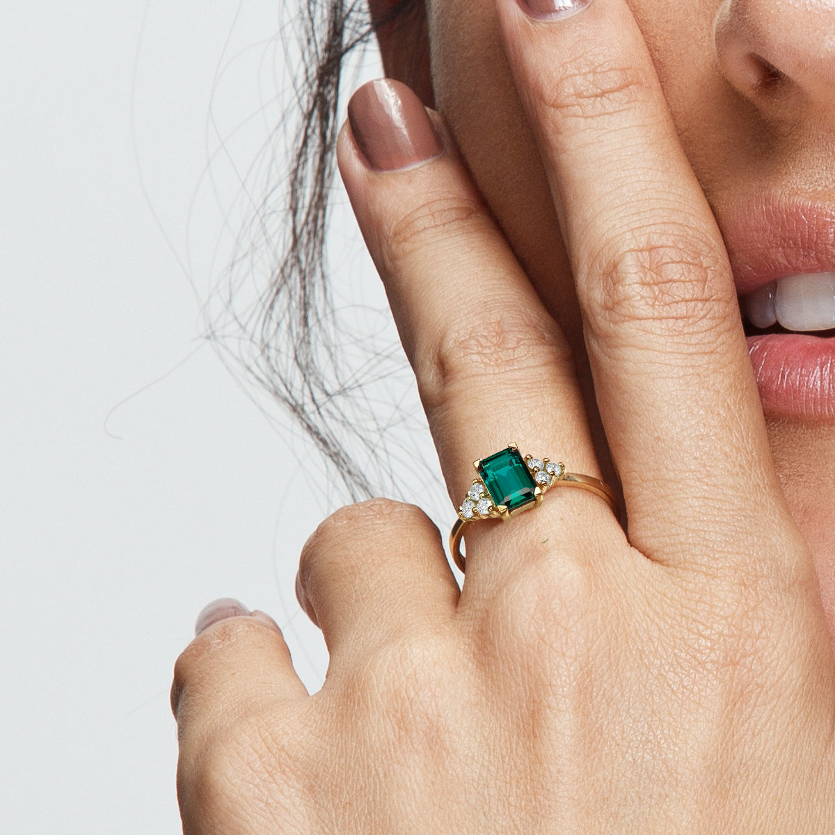 An engagement ring set with a rectangular lab emerald and 6 sided diamonds