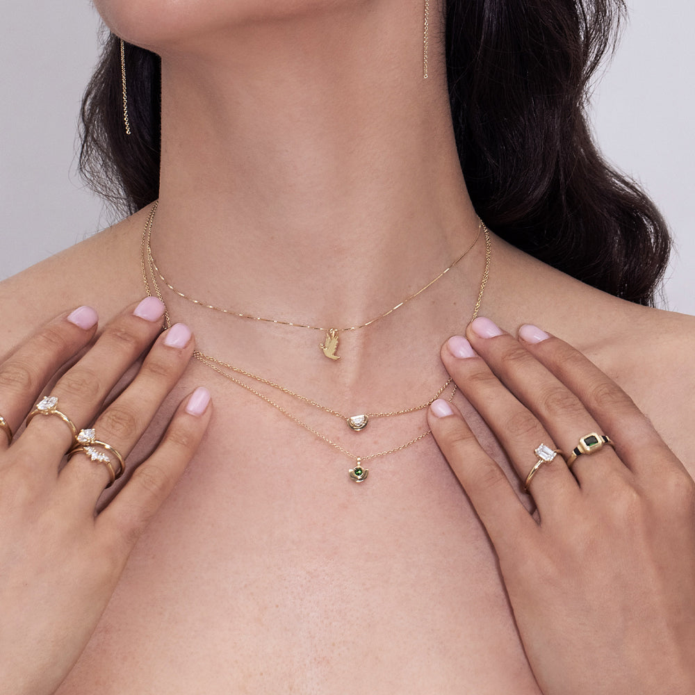 A gold necklace with a dove of peace pendant and an olive leaf