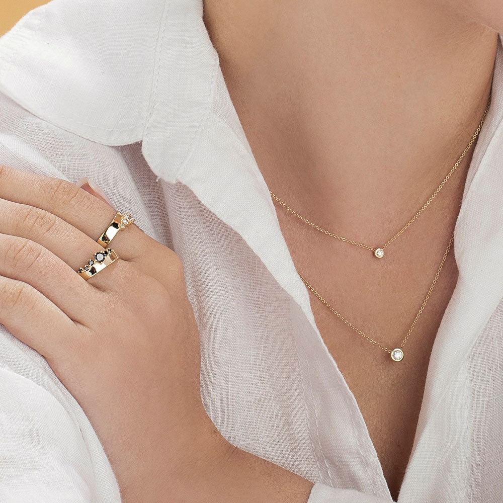 A diamond pendant in a glass setting, attached to a chain on both sides, 0.10ct diamond