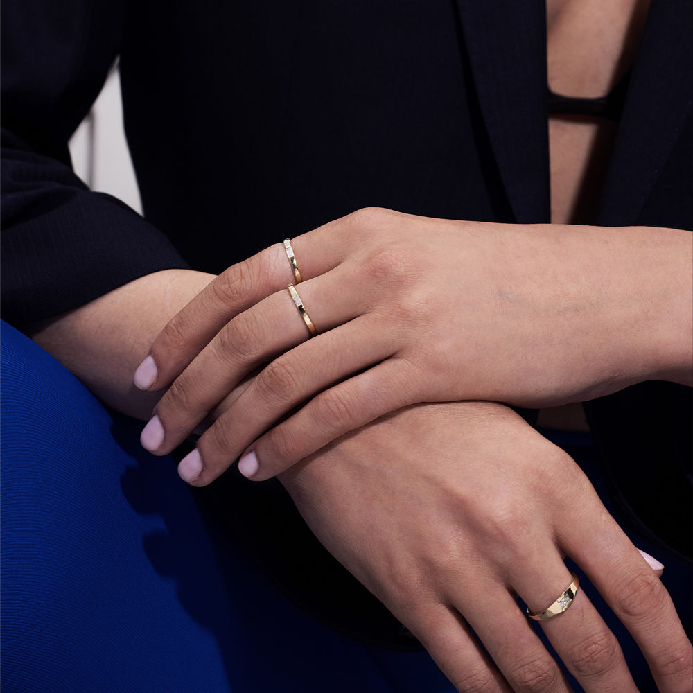 A thin flat gold ring set with a baguette-cut laboratory diamond