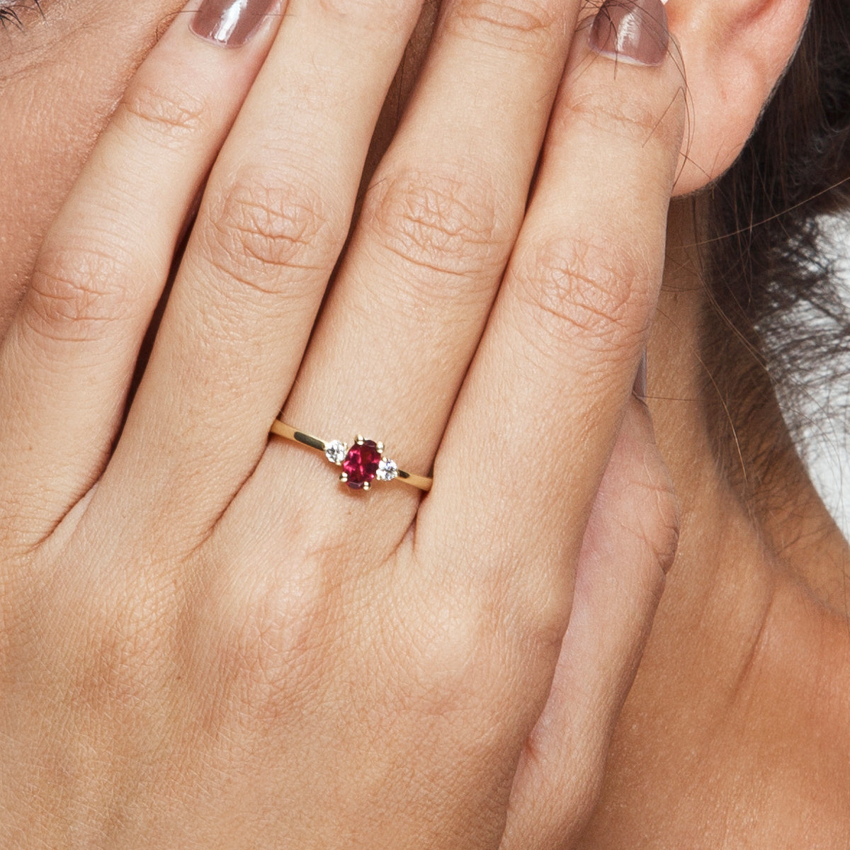 A gold ring set with an oval garnet and 2 side diamonds