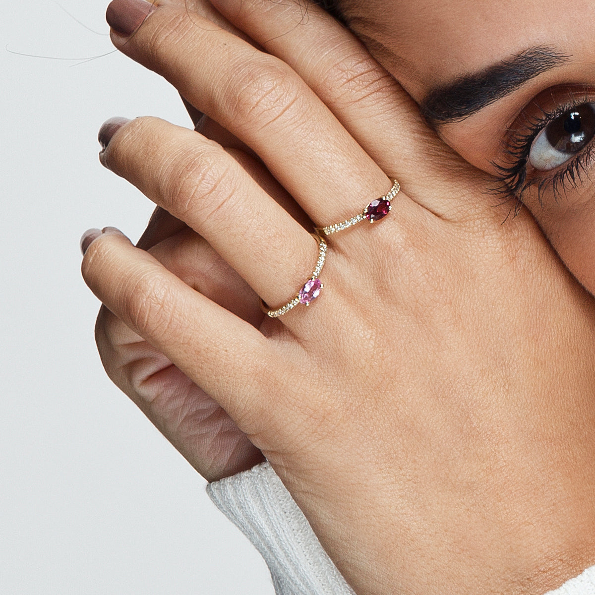 A gold ring set with an oval pink sapphire and a row of diamonds on the sides