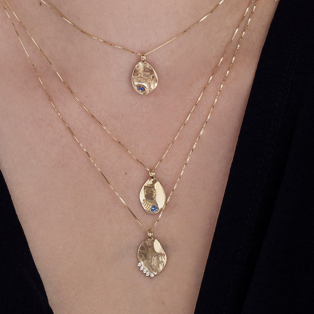 Gold necklace with an amorphous pendant with a sapphire inlaid eye decoration