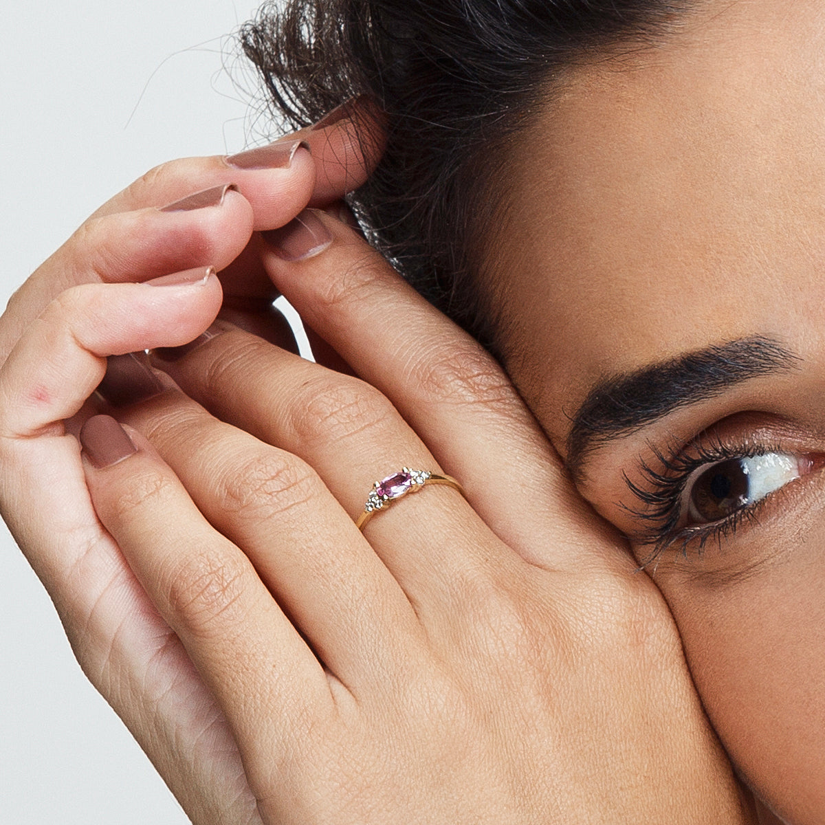 An engagement ring set with a pink sapphire in an oval shape and 6 sided diamonds