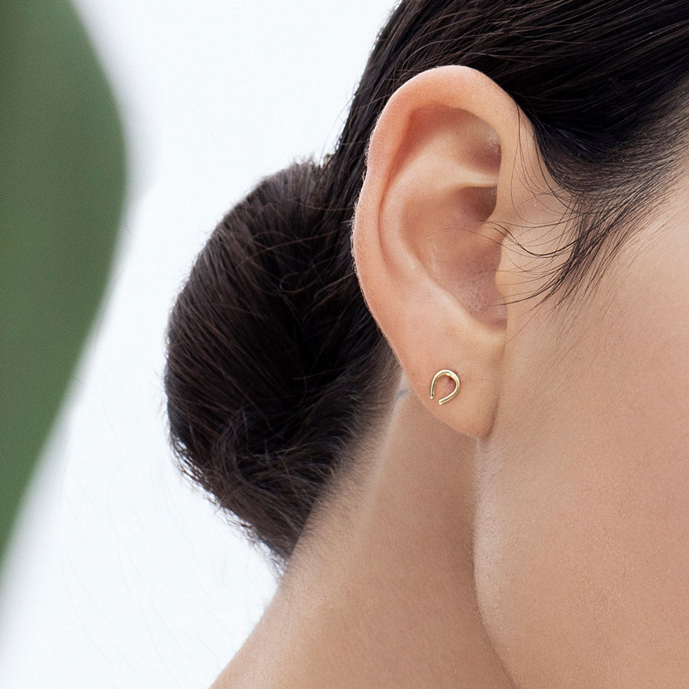 Small tight gold earrings in the shape of a horseshoe