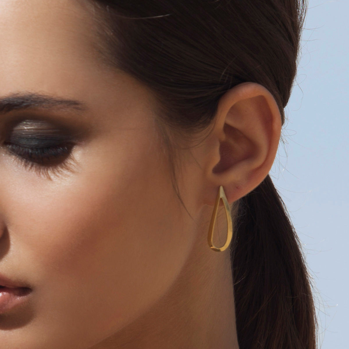 Large tight gold earrings in the shape of a drop