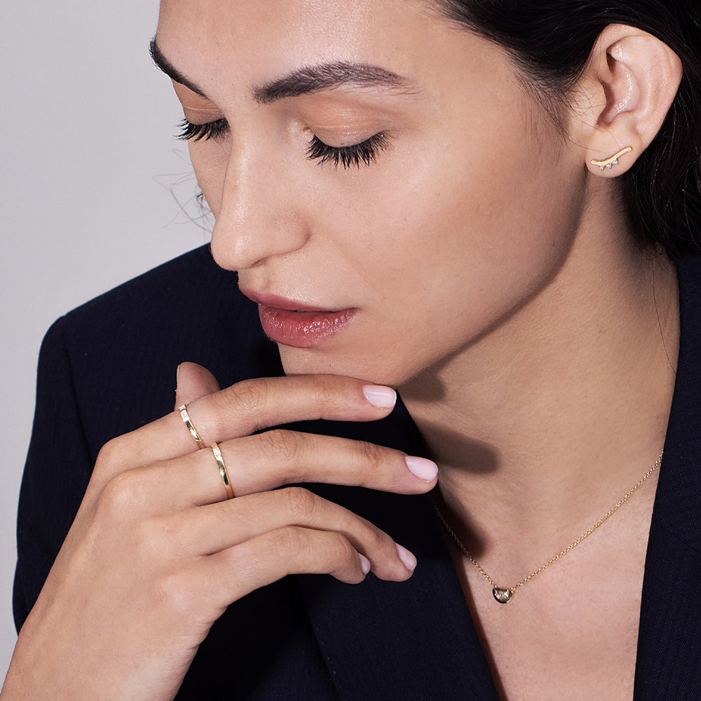 A thin flat gold ring set with a baguette-cut laboratory diamond
