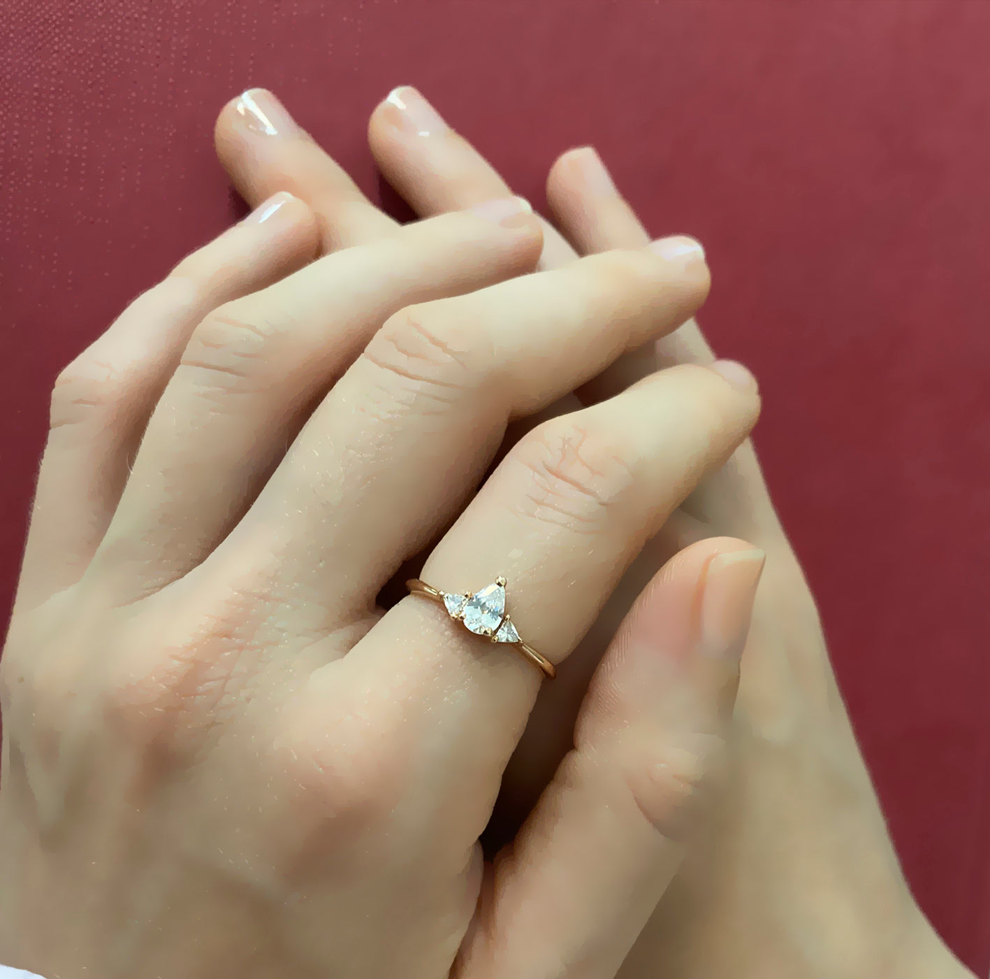 An engagement ring set with a central drop-cut diamond and triangular-cut diamonds on the sides