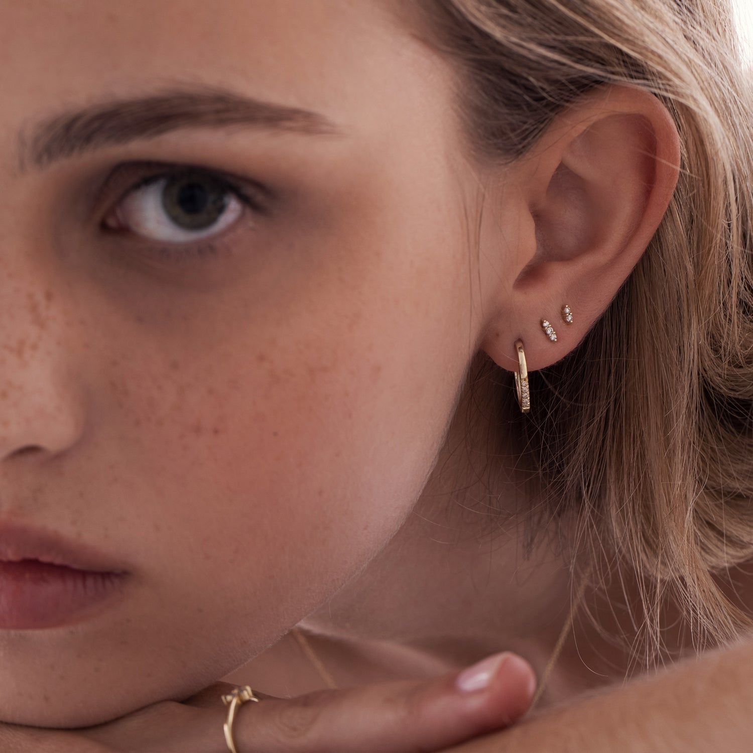 Oval shaped gold hoop earrings studded with diamonds