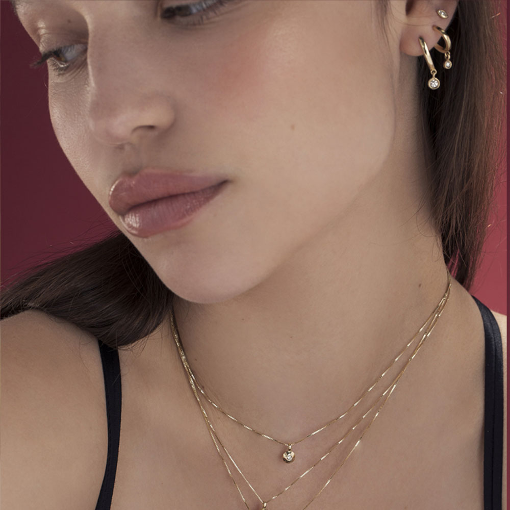 Small attached gold hoop earrings in the shape of a drop
