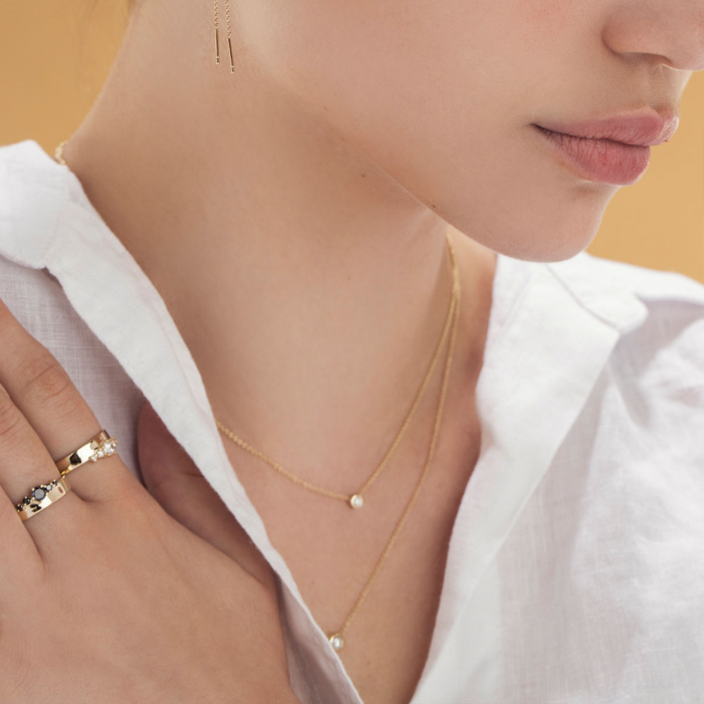 A diamond pendant in a glass setting, attached to a chain on both sides, 0.05ct diamond