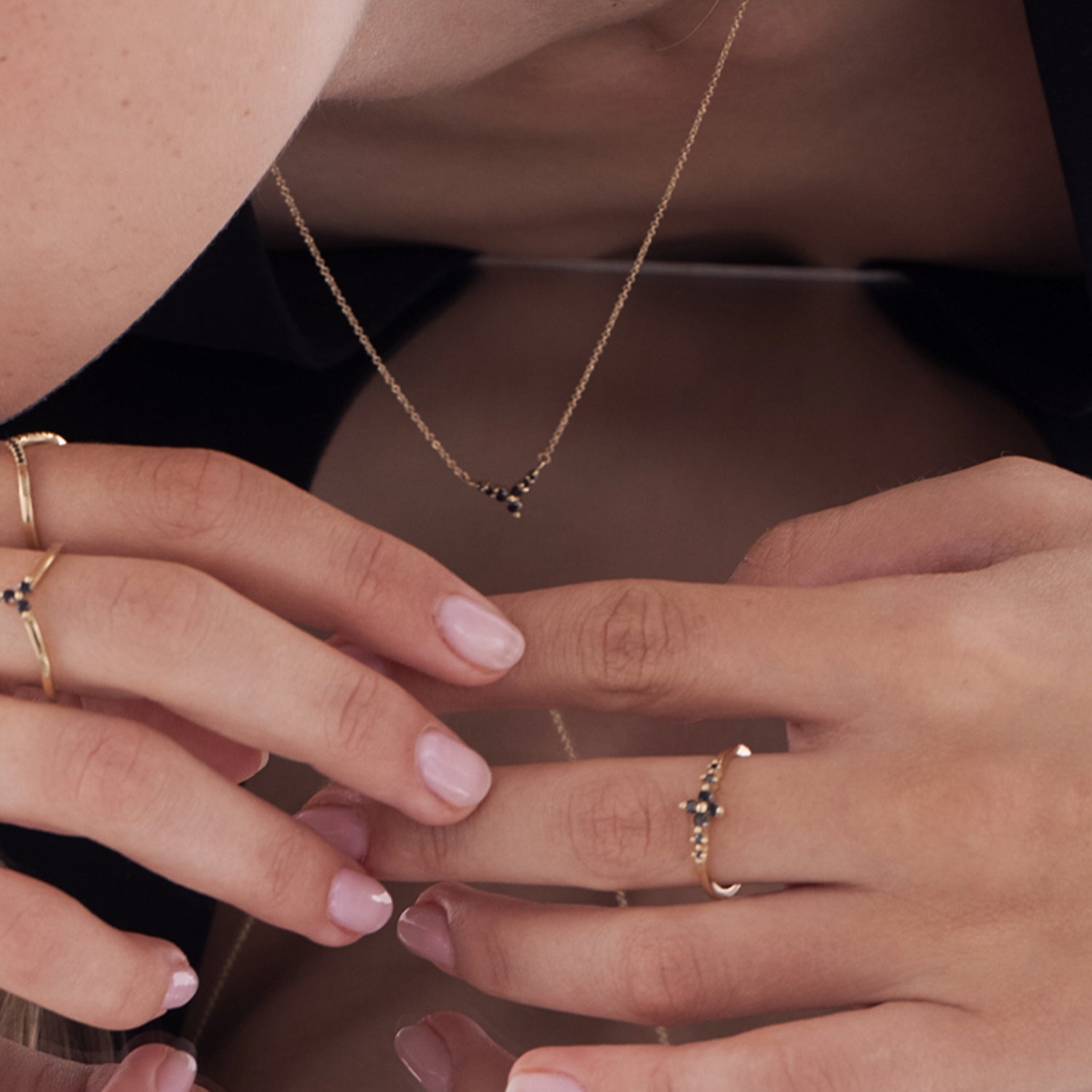 A delicate and thin gold ring set with black diamonds in the shape of a central flower and side diamonds