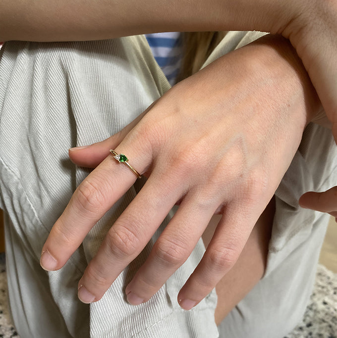 A gold ring set with a diamond and green tourmaline in a trillion cut