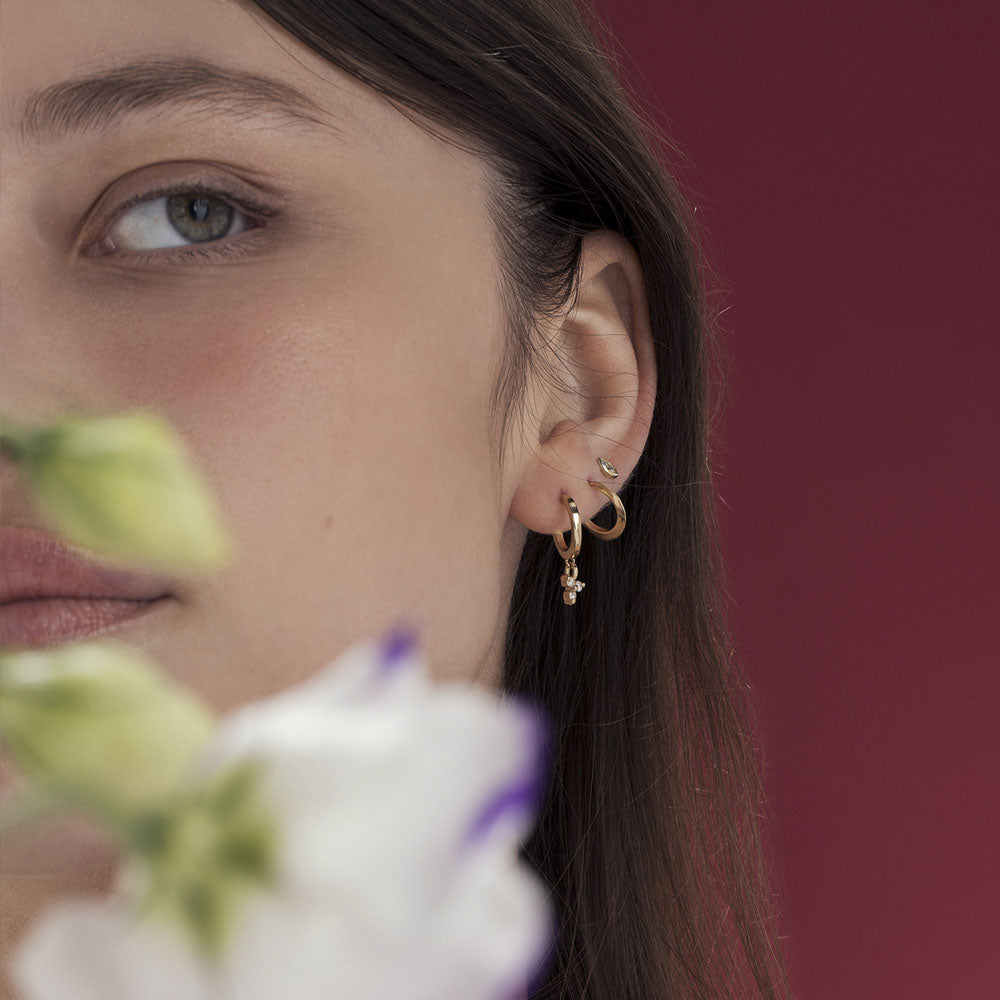 Gold hoop earrings with a triangular pendant with 3 white diamonds