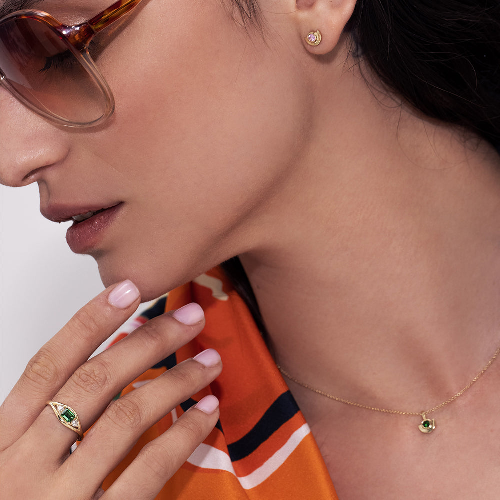 Gold earrings, tight, small, in the shape of a semicircle embedded with a pink sapphire