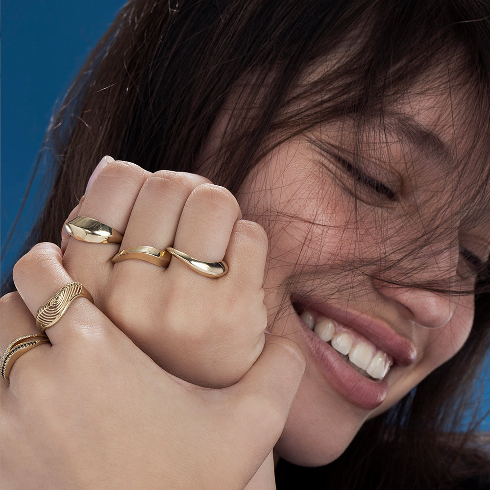 A wide geometric gold ring in a wave shape