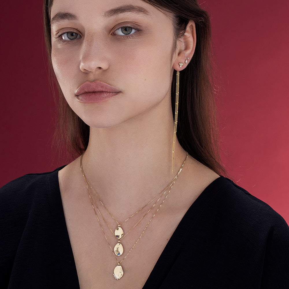 Gold necklace with an amorphous pendant decorated with a fish inlaid with a sapphire stone