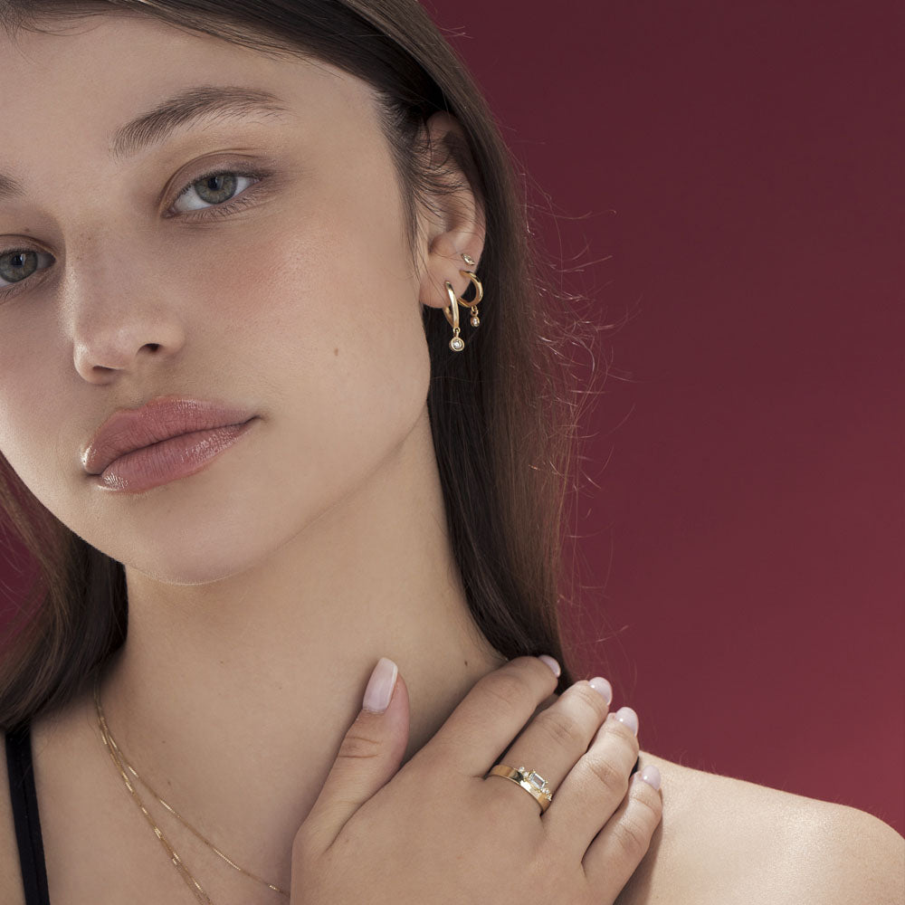 Special elongated hoop earrings, with a swinging diamond in a gold frame
