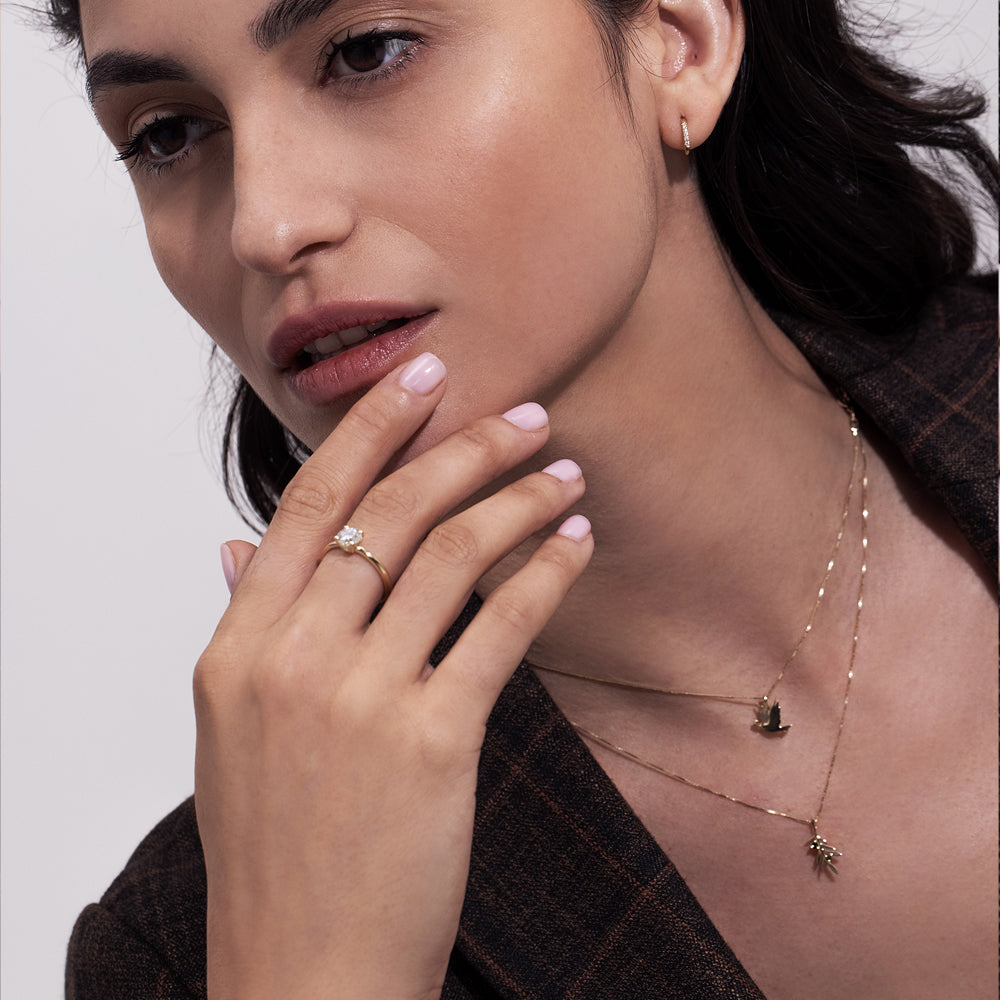 A gold necklace with a dove of peace pendant and an olive leaf