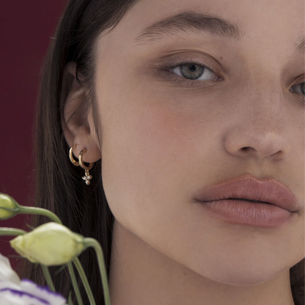 Gold hoop earrings with a triangular pendant with 3 white diamonds