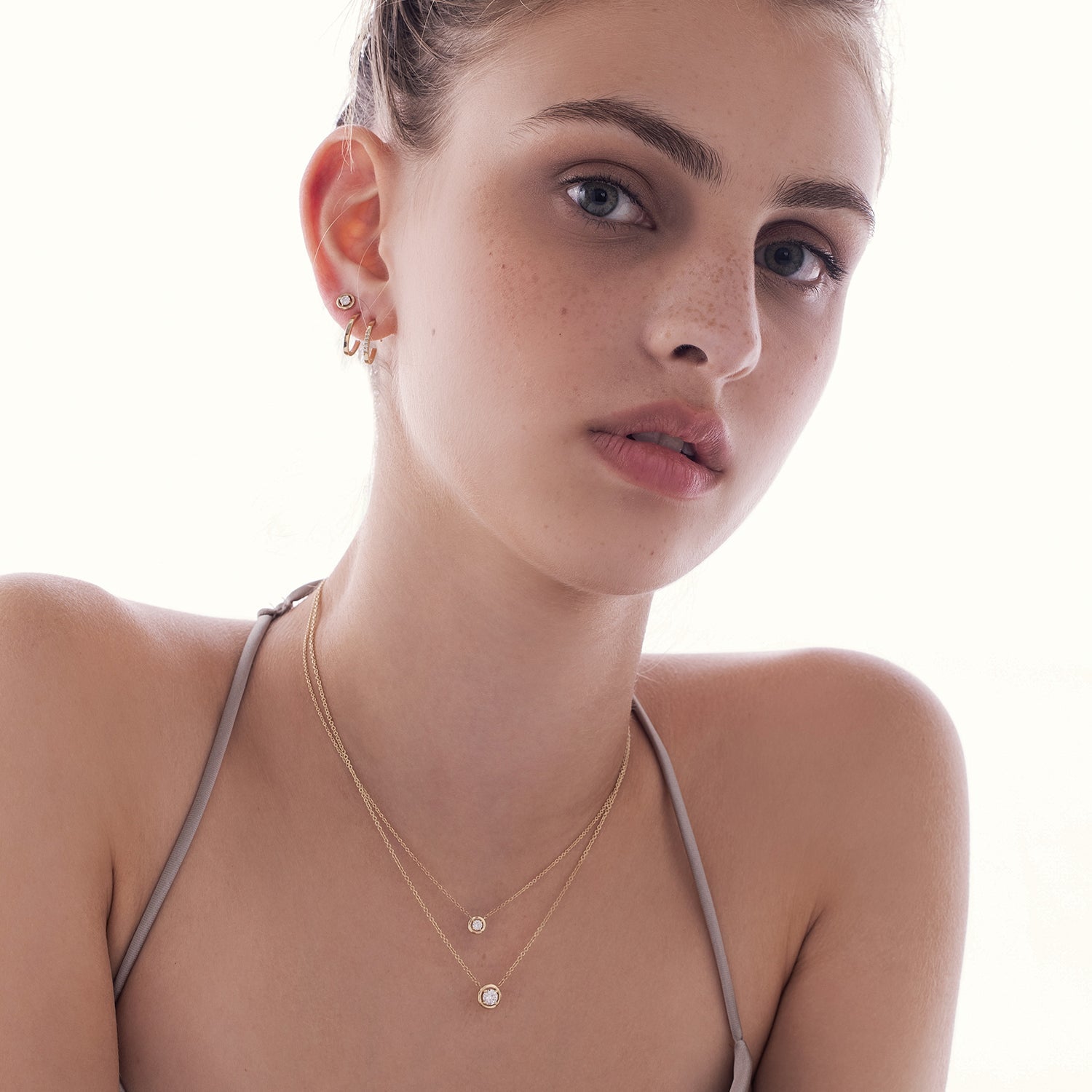 Oval shaped gold hoop earrings studded with diamonds