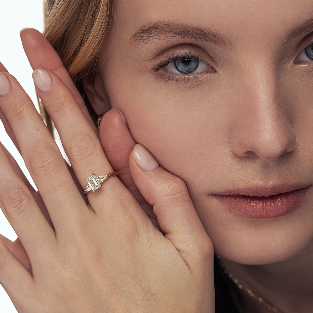 An engagement ring set with laboratory diamonds. Emerald cut central diamond and two drops