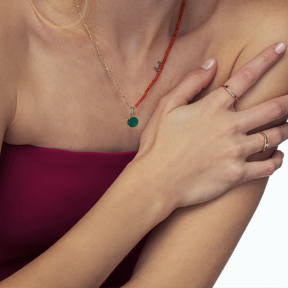 A gold chain combined with natural coral, in the center a green onyx pendant with an oval cut