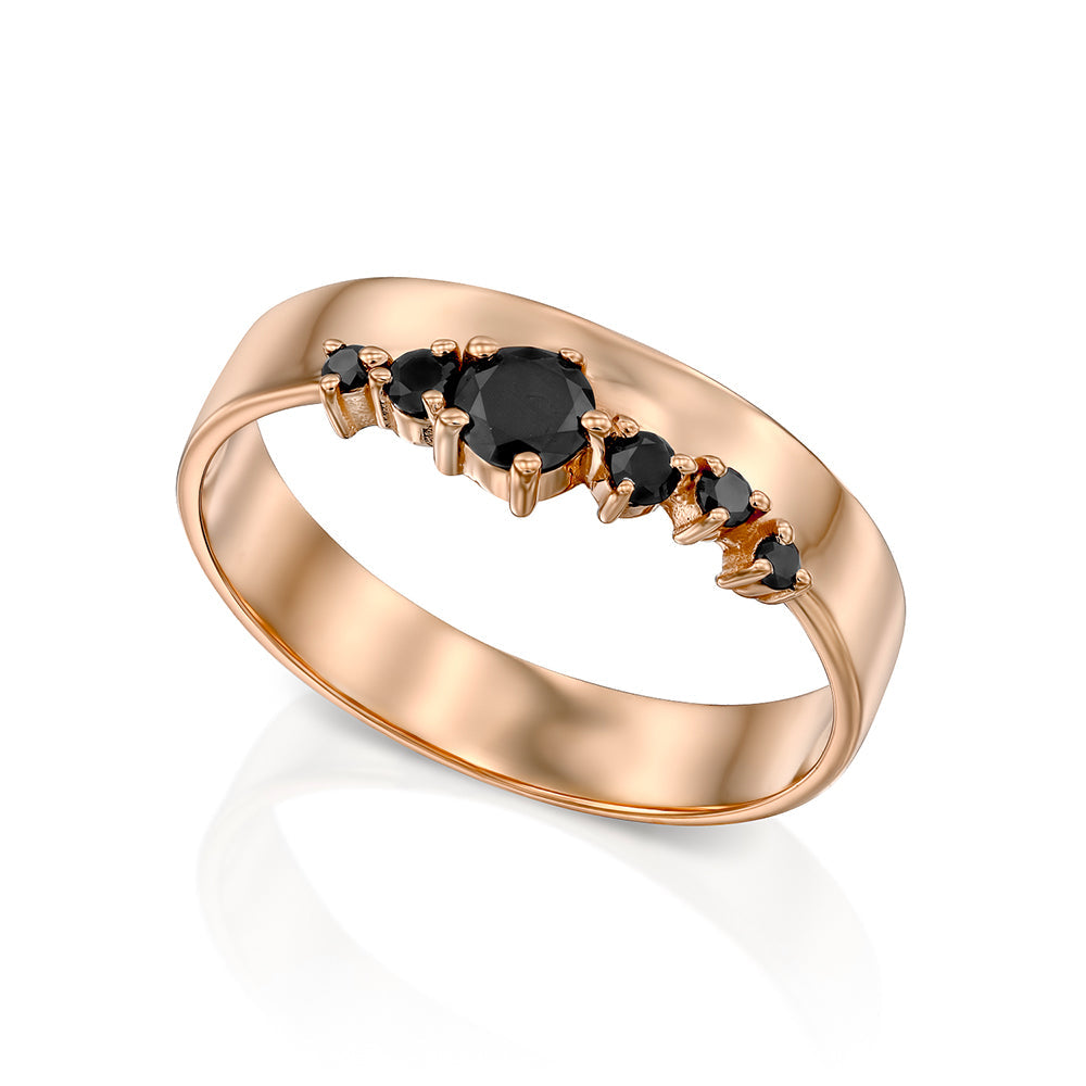 A wide gold ring with a special asymmetrical setting of black diamonds