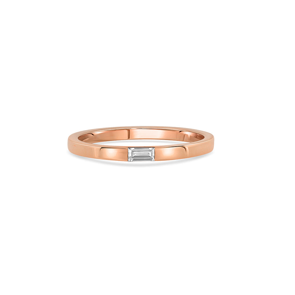 A thin flat gold ring set with a baguette-cut laboratory diamond