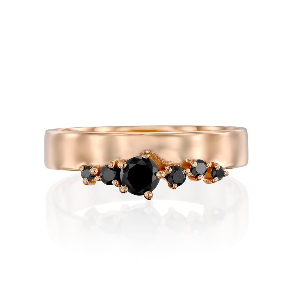 A wide gold ring with a special asymmetrical setting of black diamonds