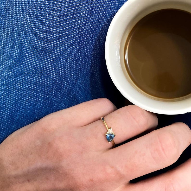A gold ring set with a diamond and a trillion-cut sapphire