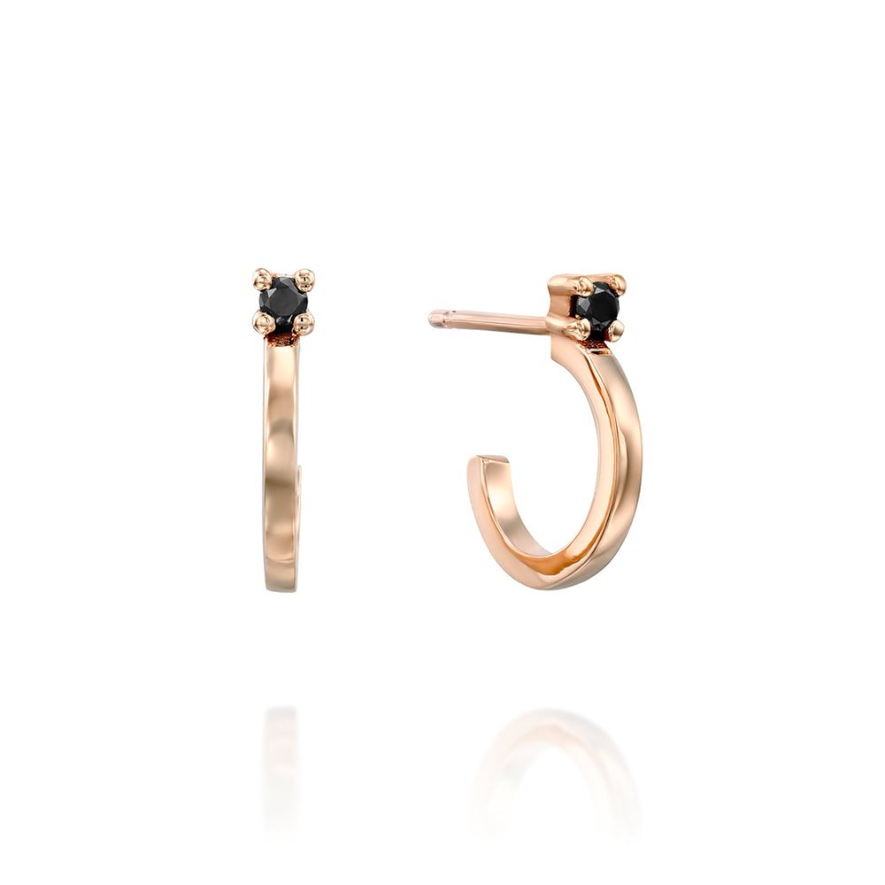 Small gold hoop earrings set with a black diamond close to the ear