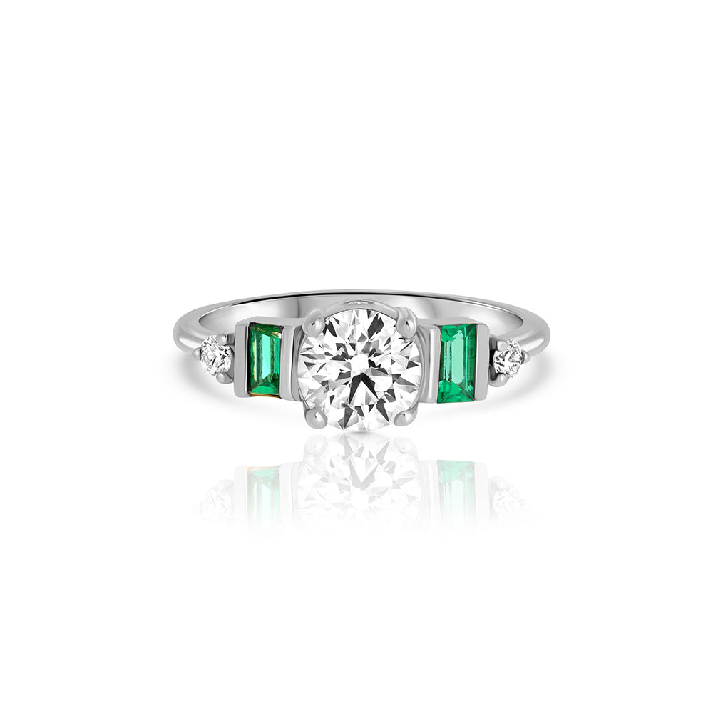 An engagement ring in gold and laboratory diamonds in a unique design of round diamonds and emeralds