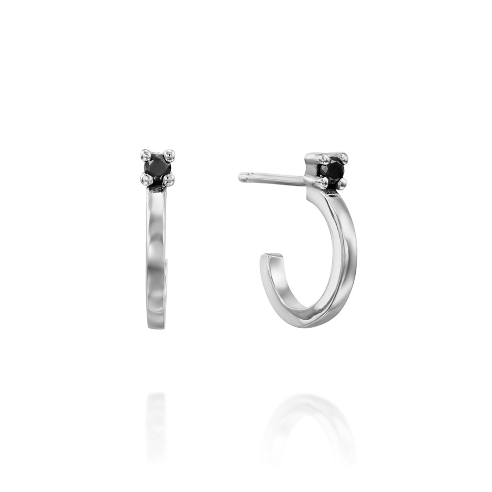 Small gold hoop earrings set with a black diamond close to the ear