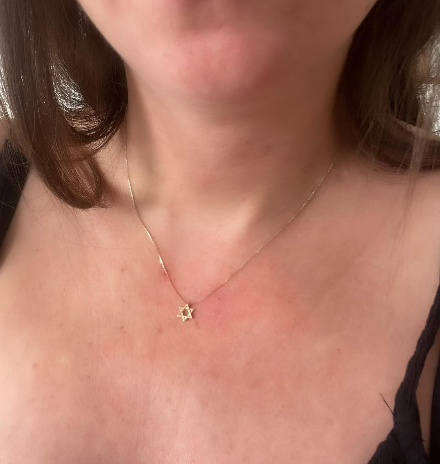 A gold chain with a small gold Star of David pendant threaded onto a gold chain