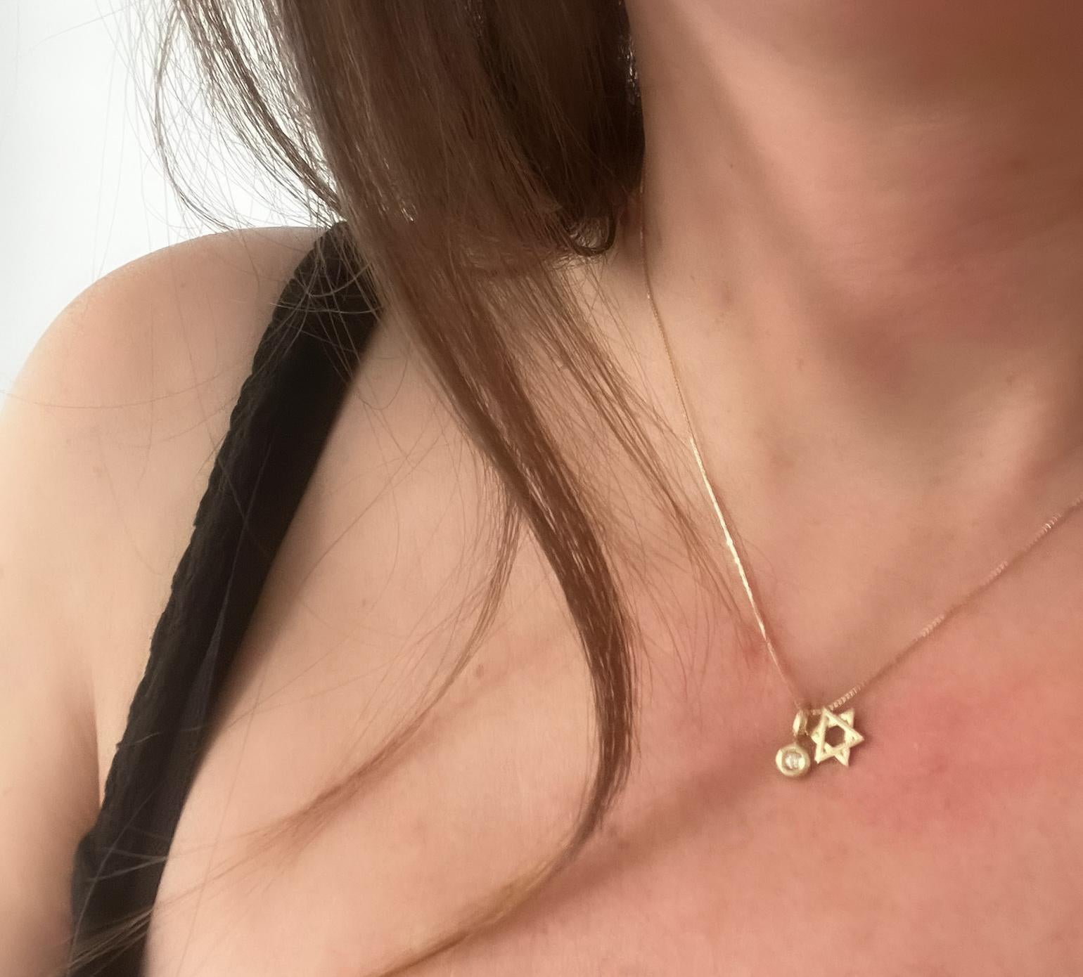A small gold Star of David pendant threaded onto a gold chain combined with a diamond pendant