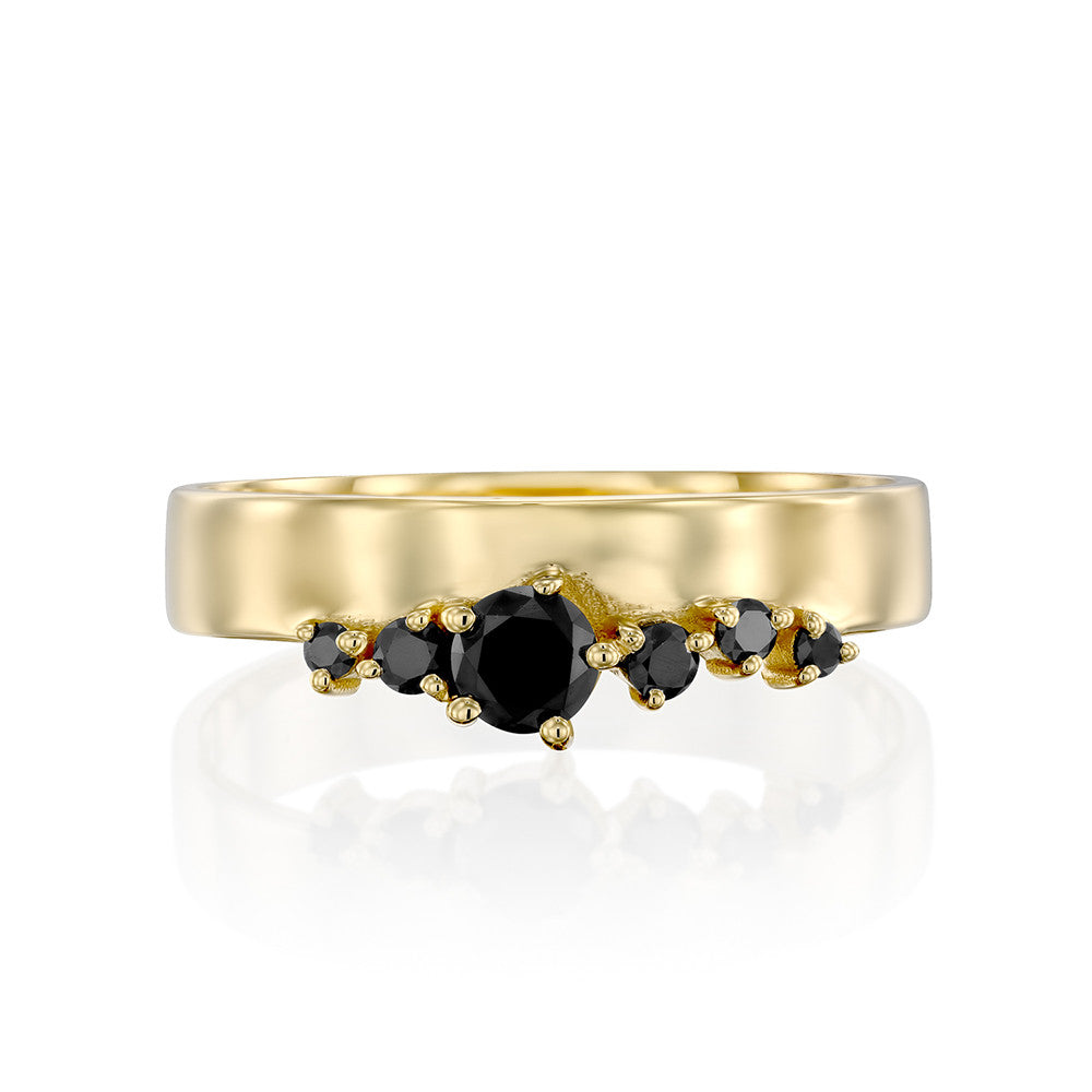 A wide gold ring with a special asymmetrical setting of black diamonds