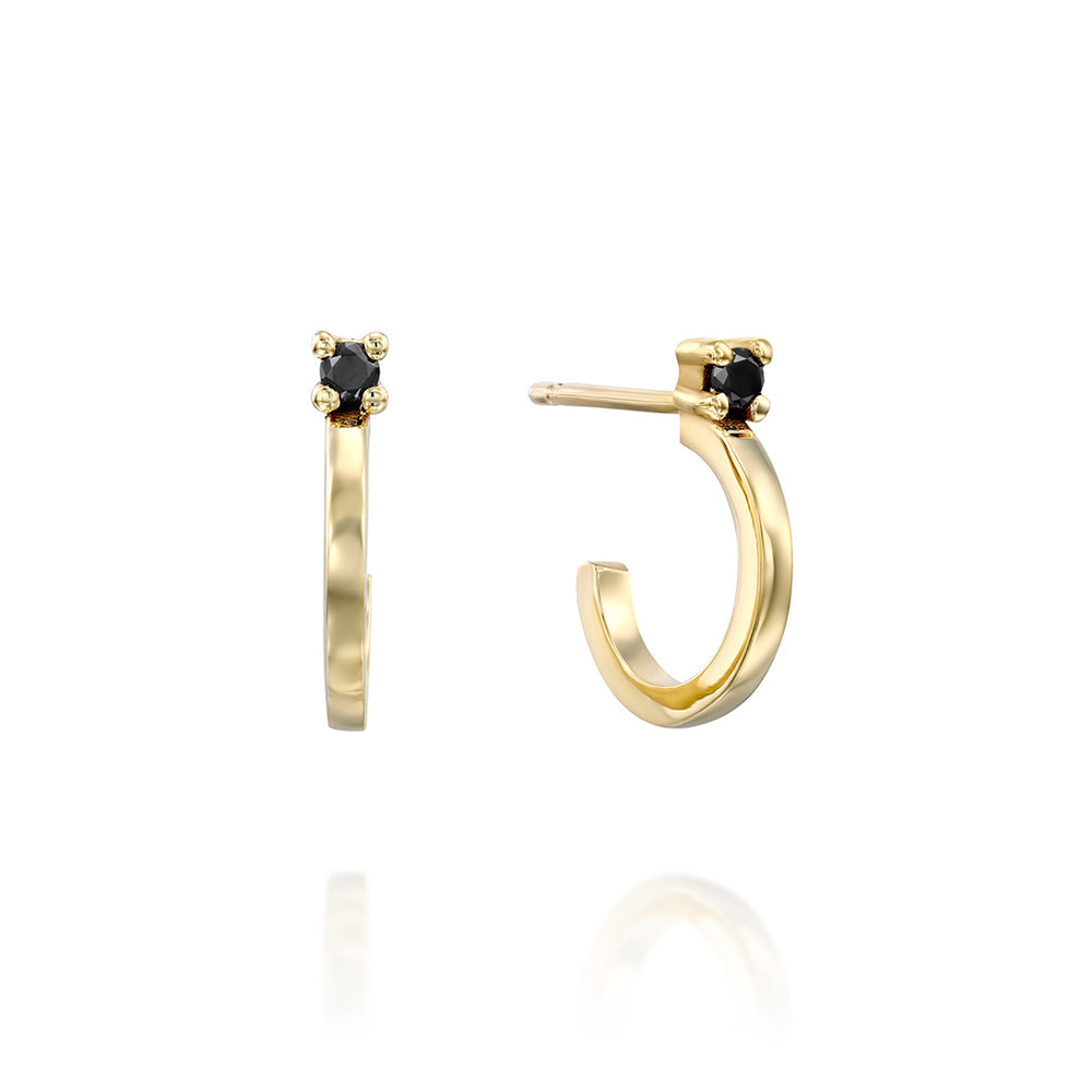 Small gold hoop earrings set with a black diamond close to the ear
